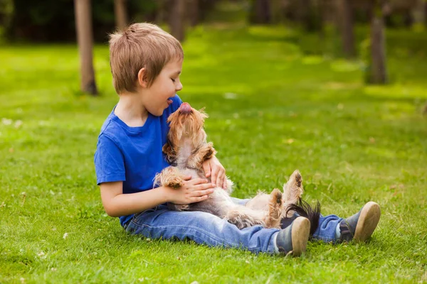 O menino feliz está se divertindo com seu cão — Fotografia de Stock