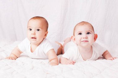 İki bebek ikiz, beyazların arasında göbeğinde yatıyor.