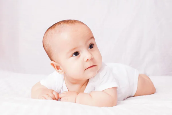 Schattige baby liggend op de buik bij de witte — Stockfoto