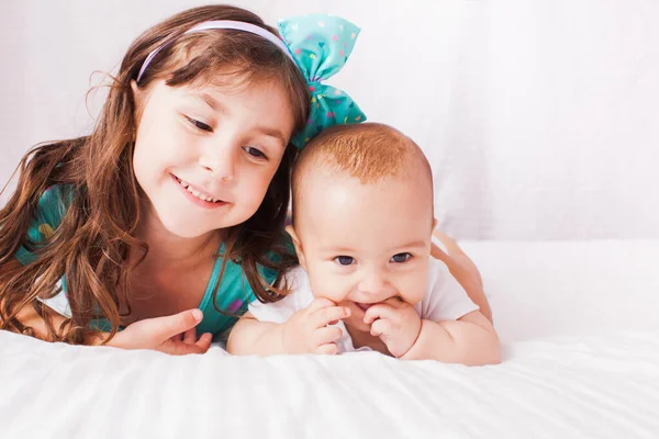 The happy little girl and baby are lying in the bedroom — Stock Photo, Image
