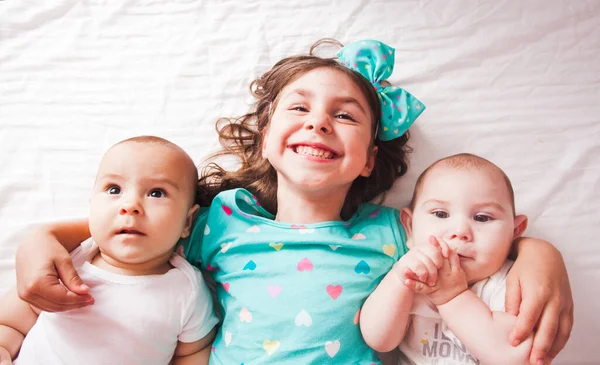 La chica feliz se regocija en su hermano pequeño y su hermana — Foto de Stock