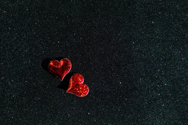 Pequeños corazones rojos en el fondo negro brillante con espacio de copia — Foto de Stock