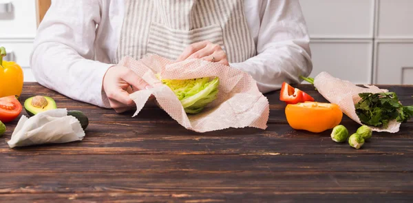 Queijo de embrulho feminino em envoltórios de cera de abelha na cozinha — Fotografia de Stock