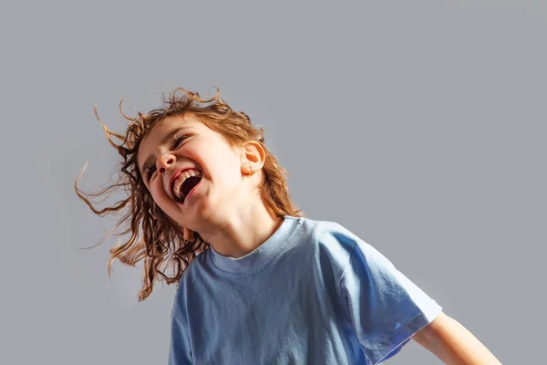 Маленькая девочка прыгает на сером фоне — стоковое фото