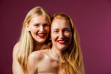 Mor arka planda sarılan iki güzel kız kardeş.