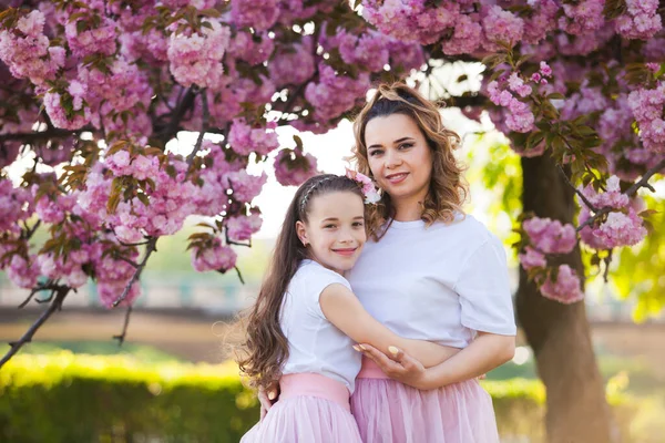 Mamá y su hija están de pie junto a una planta tierna — Foto de Stock