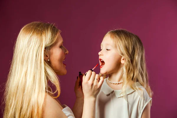 Close-up mother colouring lips of her daughter — Stock Photo, Image