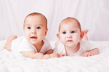 İki bebek ikiz, beyazların arasında göbeğinde yatıyor.
