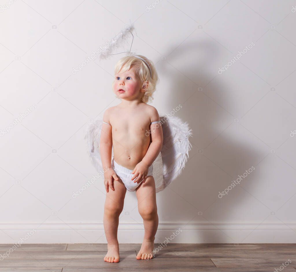 Fotos de El lindo bebé está usando un disfraz de Cupido en la habitación -  Imagen de © oksixx #449490296