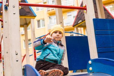 Üzgün çocuk dışarıda tek başına oyun oynuyor.