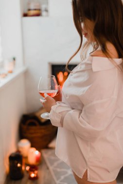 Çekici kız şöminenin yanında bir kadeh şarapla dinleniyor.