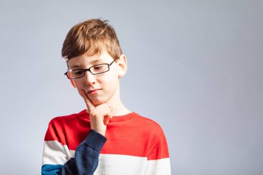Düşünceli sarı saçlı gözlüklü çocuk işaret parmağını tutuyor.