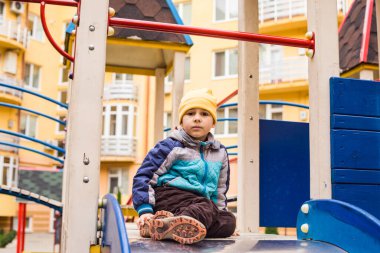 Üzgün çocuk dışarıda tek başına oyun oynuyor.