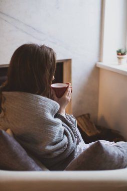 Sıcak içkisi olan kadın şöminenin yanında dinleniyor.