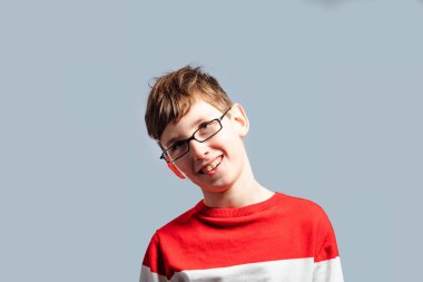 Komik çocuk gri arka planda yüzünü buruşturuyor.