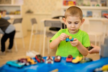 Tatlı çocuk evde oyuncak arabalarla oynuyor.