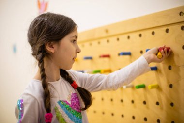 Kız tahta tahta çivilerle oynuyor.