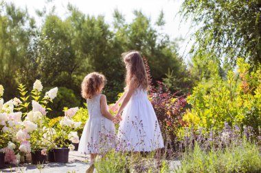Çiçeklerin arasında dans eden küçük kızlar