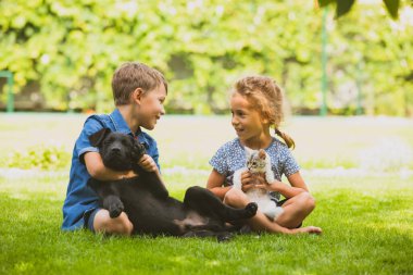 Neşeli erkek ve kız kardeşler parkta sohbet ediyorlar.