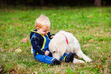 Mutlu bebek çimenlikte köpeğiyle