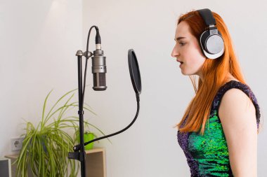 Kız evde profesyonel aletlerle şarkı söylüyor.