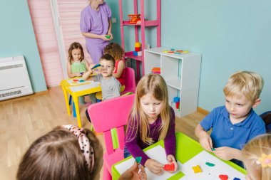 Hocaları olan mutlu çocuklar plastikten heykel yapıyorlar.