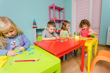 Çocuklar anaokulunda birlikte parlak şeyler yaratıyorlar.