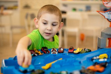 Tatlı çocuk evde oyuncak arabalarla oynuyor.