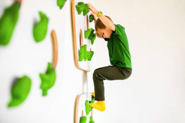 Çocuk içerideki yapay kayalara tırmanıyor.