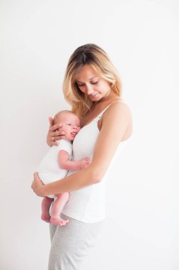 Güzel, gülümseyen bir anne kucağında yeni doğmuş bir bebek