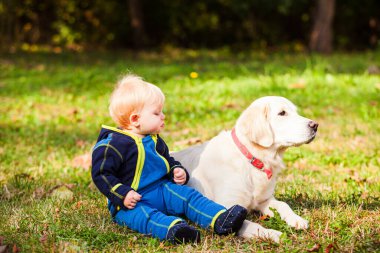 Mutlu bebek çimenlikte köpeğiyle