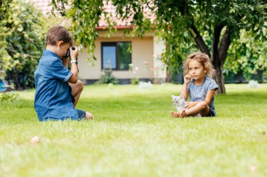 Kedili çocukların arka bahçede fotoğrafları çekiliyor.
