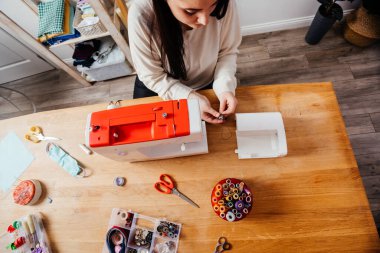 Kadın elleri ipliği dikiş makinesine dolduruyor
