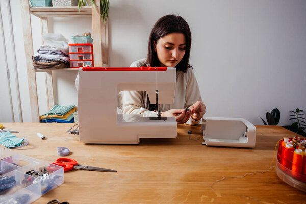 Woman hands filling thread into sewing machine spool