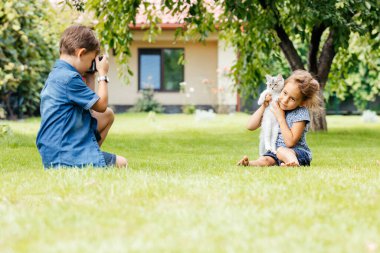 Kedili çocukların arka bahçede fotoğrafları çekiliyor.
