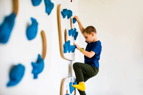 El chico está escalando rocas artificiales en el interior — Foto de Stock