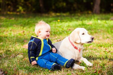 Mutlu bebek çimenlikte köpeğiyle