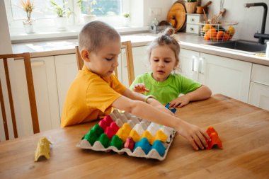 Kağıtları birleştirmekle meşgul olan sevimli kardeşler.