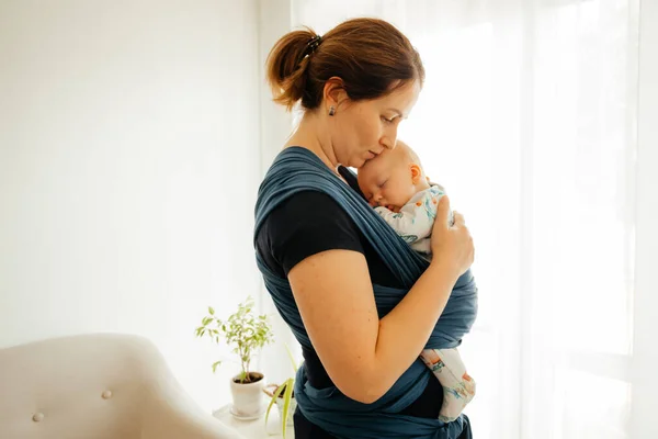 Концепция воспитания привязанности. Молодая мать с ребенком в стропе — стоковое фото