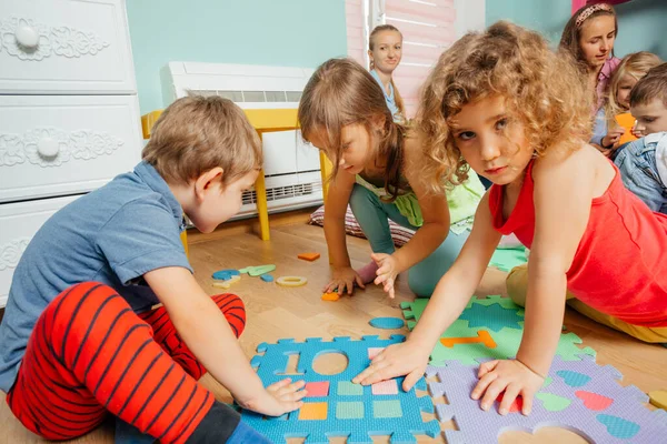 바닥에 놓여 있는 부드러운 퍼즐을 가지고 노는 귀여운 어린이들 — 스톡 사진