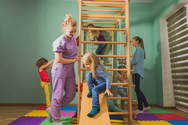 Teacher supports children during active games at preschool