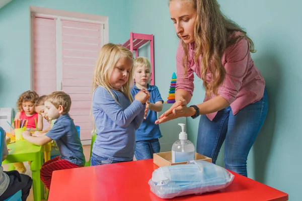 Insegnante mostra i bambini piccoli come sanificare le mani — Foto Stock