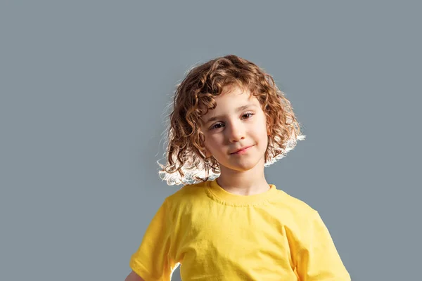 Adorável criança de 5 anos em t-shirt amarela posando em cinza — Fotografia de Stock