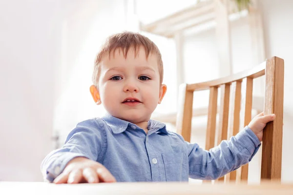 O menino bonito da criança está sentado na mesa — Fotografia de Stock