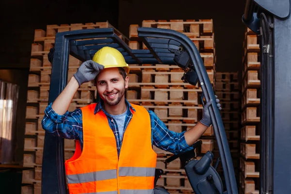 Sorrindo homem posando perto empilhadeira industrial no armazém — Fotografia de Stock