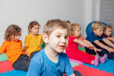 Meraklı anaokulu çocuğu grup jimnastiğinin keyfini çıkarıyor.