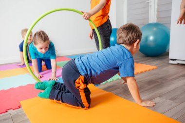 Kıvırcık kız hula çemberlerinden sürünerek geçiyor.