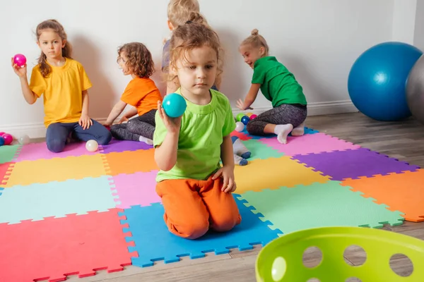 Милый мальчик играет с маленькими шариками и пластиковой корзиной — стоковое фото