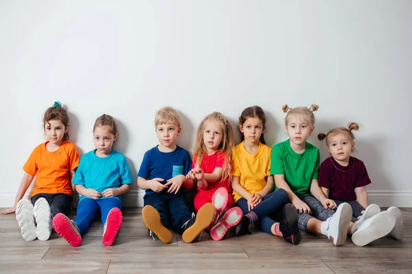 壁の近くの床に座っている陽気な子供たち — ストック写真