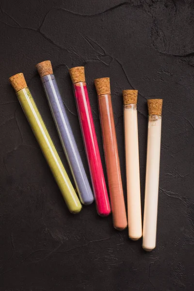 Plant based powders in glass tubes on black — Stock Photo, Image